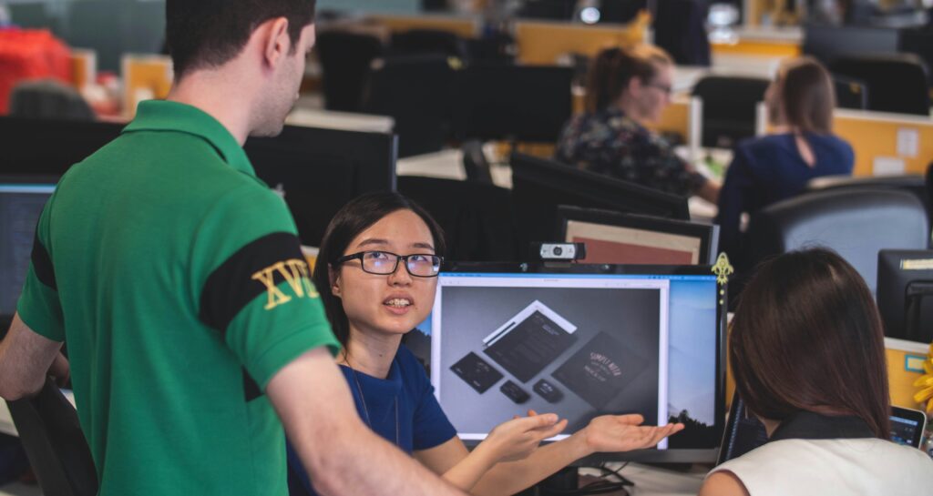 Three people discuss in a computer lab